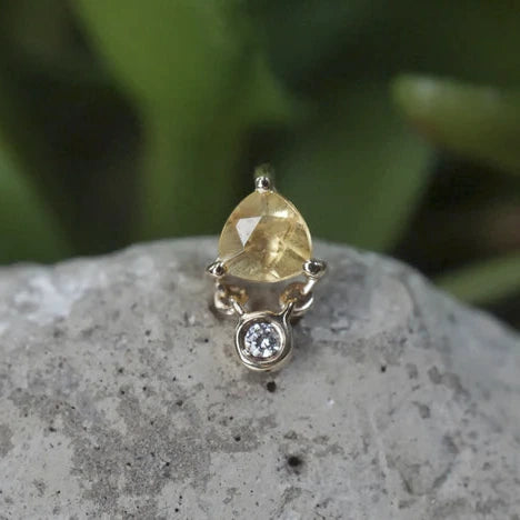 Ring with a yellow gemstone on a stone surface with a blurred green background
