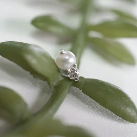 Pearl earring on a green leaf with a blurred background